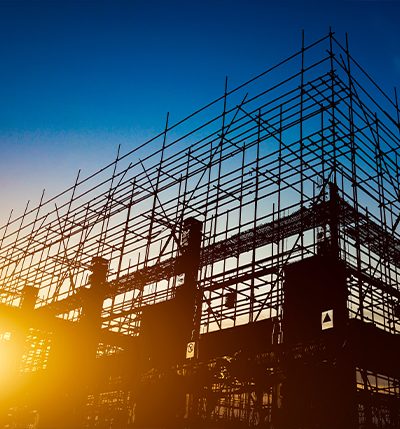 Échafaudage d'un bâtiment en construction à contre-jour, au coucher du soleil
