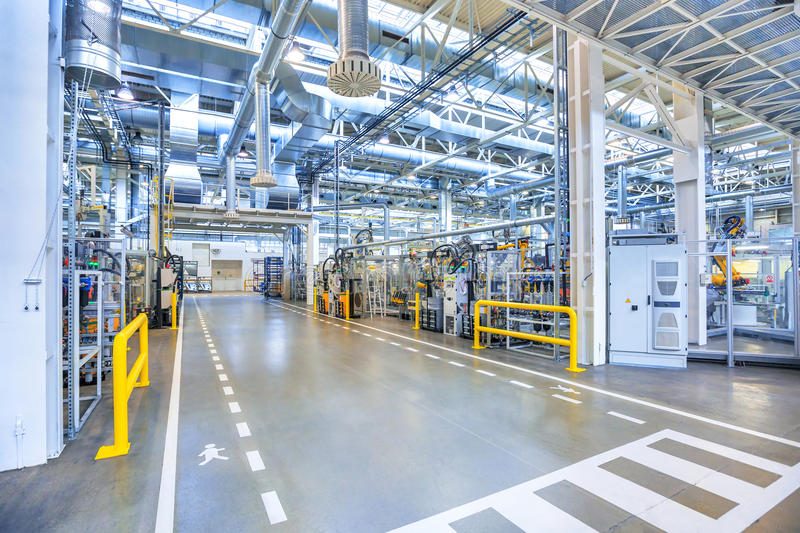 Halle de production industrielle au sol clair, avec allées de circulation marquées au sol