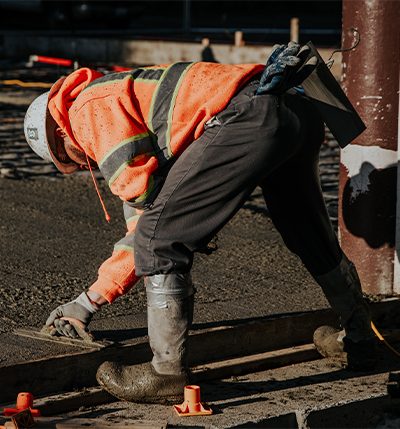 Ouvrier en tenue haute visibilité lissant une chape de mortier
