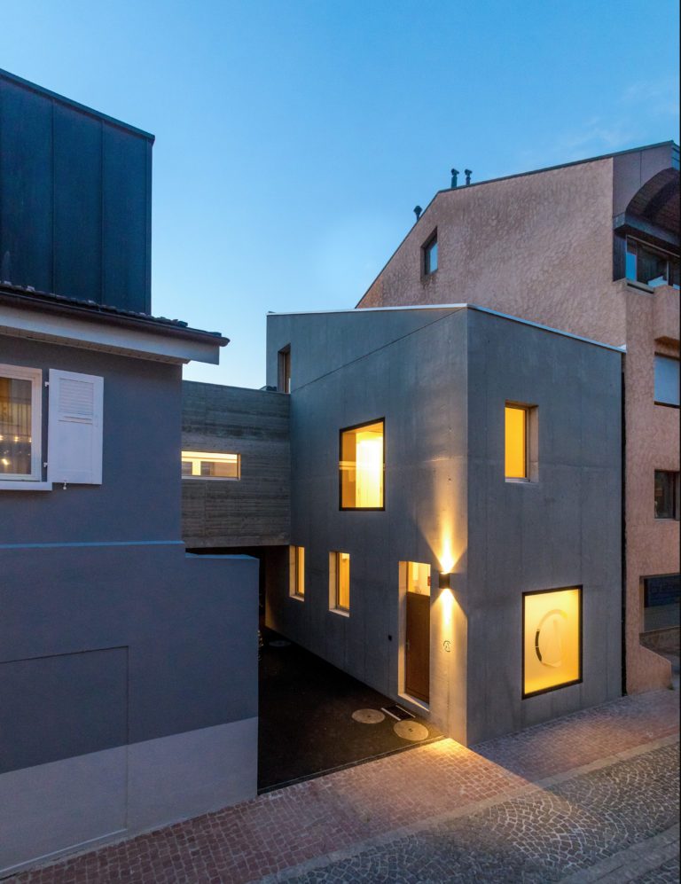 Bâtiment contemporain en béton apparent, éclairé à la tombée de la nuit